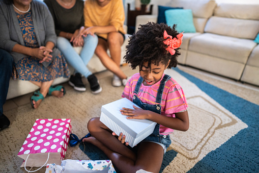 Girl child opening a gift on her birthday at home