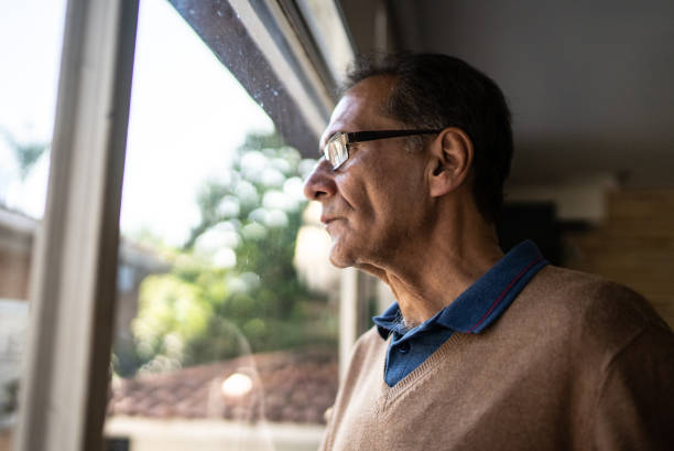 istock Senior man contemplating while looking through the window at home 1490772042