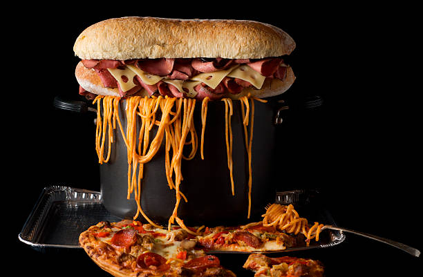 Food plate piled high Large pot full of spaghetti noodles overflowing, topped with pastrami and swiss cheese submarine sandwich on top of salami, sausage, and pepper pizza. large pasta pot stock pictures, royalty-free photos & images