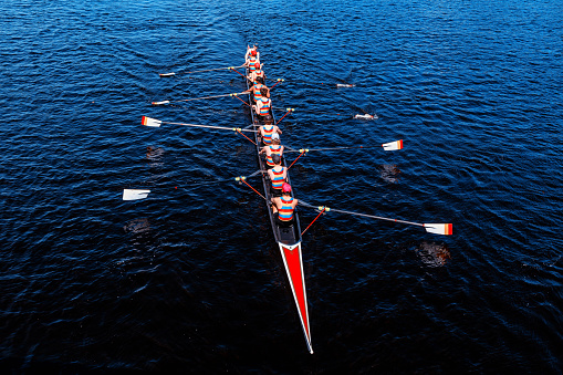 Cambridge, Massachusetts, USA - May 13, 2023: Overhead view of men rowing an eight man scull boat on the Charles River.