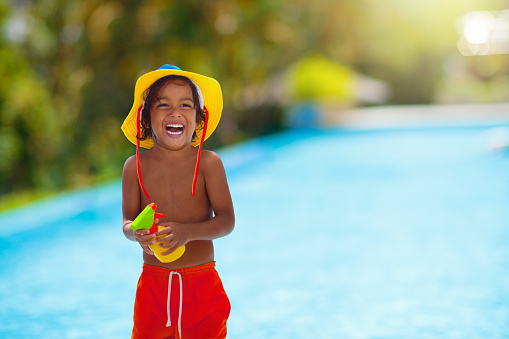Child with sunscreen at swimming pool. Sunblock for healthy tan. Safe fun in summer time. Kids play. UV protection and skin care. Little boy on beach vacation. Family holiday. Sun burn prevention.