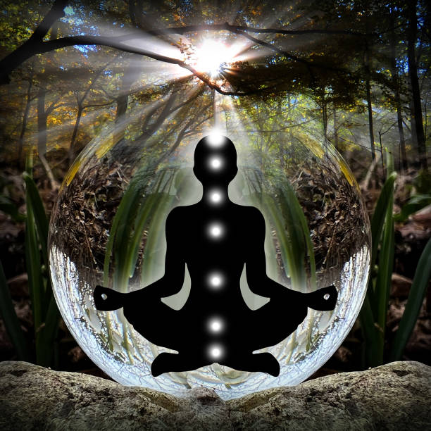 Human silhouette in yoga, lotus pose (human energy body, aura) in front of lensball (crystal ball) stock photo