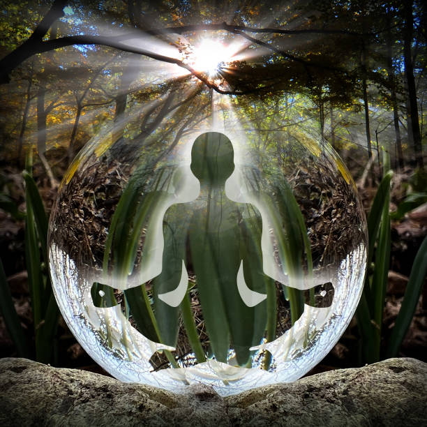 Human silhouette in yoga, lotus pose (human energy body, aura) in front of lensball (crystal ball) stock photo