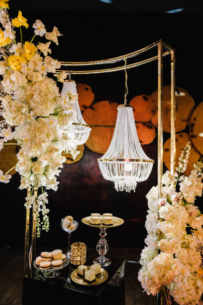 istock Delicious luxury wedding reception. Candy bar. Table with candies, dessert. Arch with large chandelier, flowers in hall restaurant. Golden rich interior with light at night. Birthday, baptism, event. 1490780327