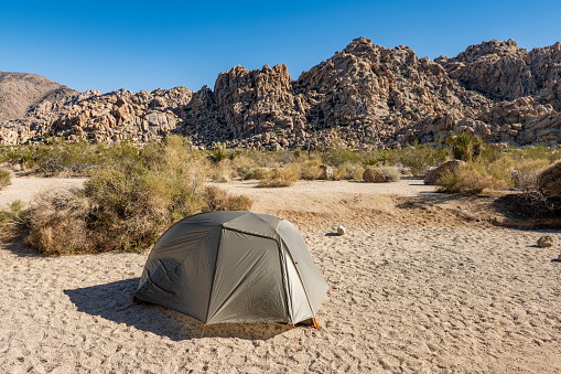 This is a wide angle photograph of a small tent setup at the Indian Cove Campground in Joshua Tree National Park in the Mojave Desert, California.
