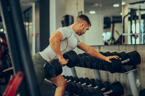 istock A muscular sportsman is leaning in a gym while lifting weights. 1490781479