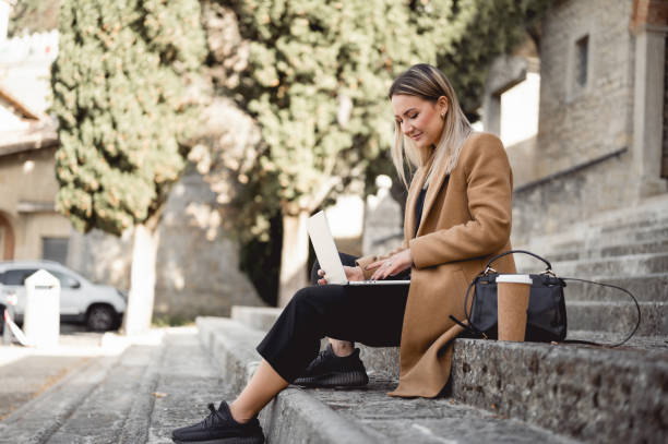 istock female student with laptop sitting on a staircase in a sunny day. 1490781761