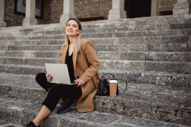 istock cheerful blonde woman relaxing outdoors with computer. 1490781904