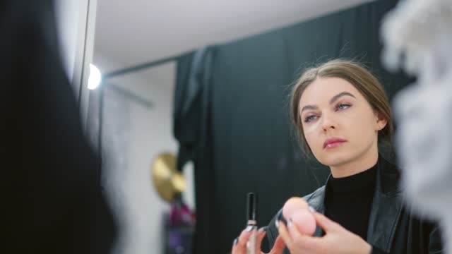 Woman applying concealer under the eye circles in a backstage