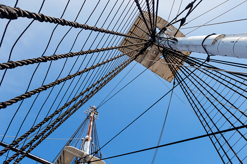 Skyward view up two masts and riggings of an old square rigger sailing ship.