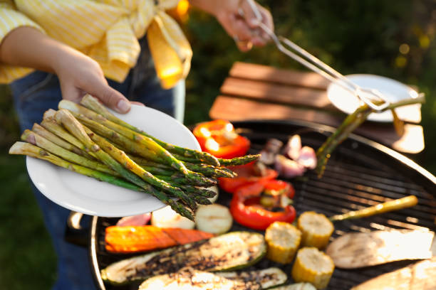 Woman cooking vegetables on barbecue grill outdoors, closeup stock photo