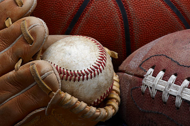 Dirty old baseball, glove, football and basketball close up shot of well worn baseball in baseball glove, football and basketball american football ball photos stock pictures, royalty-free photos & images
