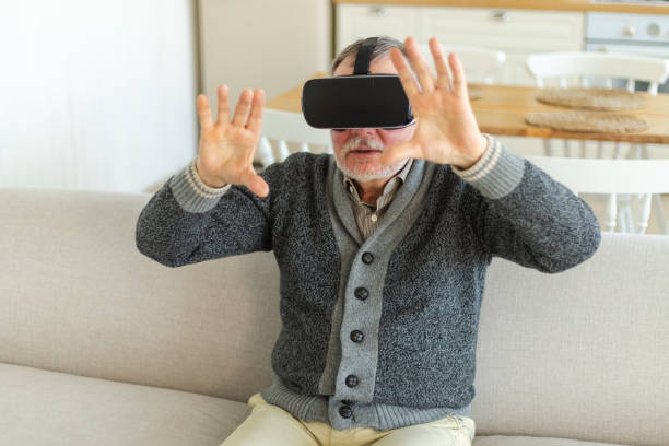 istock Excited mature senior man wearing using virtual reality metaverse VR glasses headset at home. Grandfather touching air during VR experience on virtual reality helmet. Simulation hi-tech videogame. 1490793590