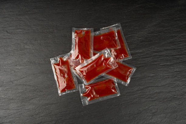 istock Ketchup in Square Plastic Bag on Black, One-Time Portion Transparent Catsup Sachet, Hot Tomato Sauce 1490796112