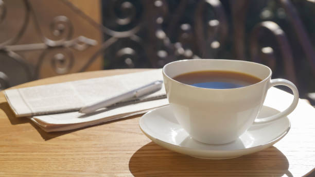 istock Cup of aromatic coffee, pen and newspaper on wooden table outdoors, space for text 1490797126