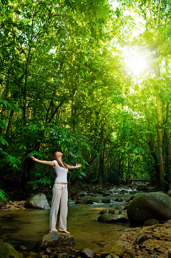 Young woman arms opened enjoying the fresh air in tropical green forest