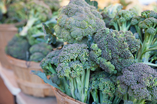 Baskets of vibrant, fresh green broccoli on display at a farmer's market.
