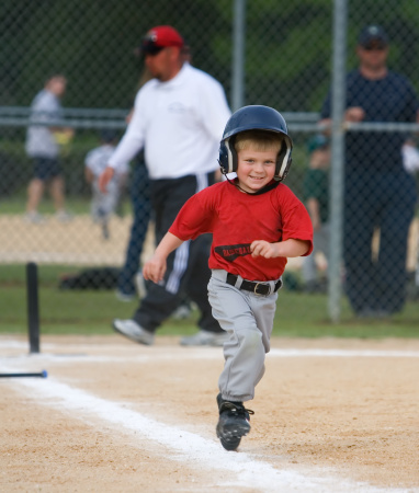 Young baseball player running and smiling during game