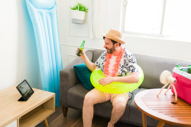 istock Cheerful relaxed man pretending to enjoy the beach at home using his tablet 1490809826