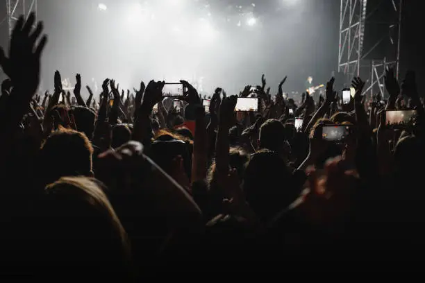 Photo of Audience with raised hands on a dance floor at a music festival.