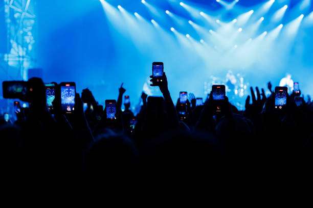 People at concert shooting video or photo using mobile phones.