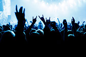 People with raised hands at a music concert. Fans in concert hall.