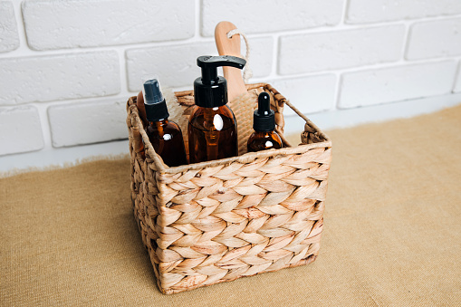 Amber bottles with cosmetic products for the bath and in a straw basket on a white background. Top view