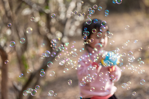 A little girl is playing with a bubble machine in the plum grove