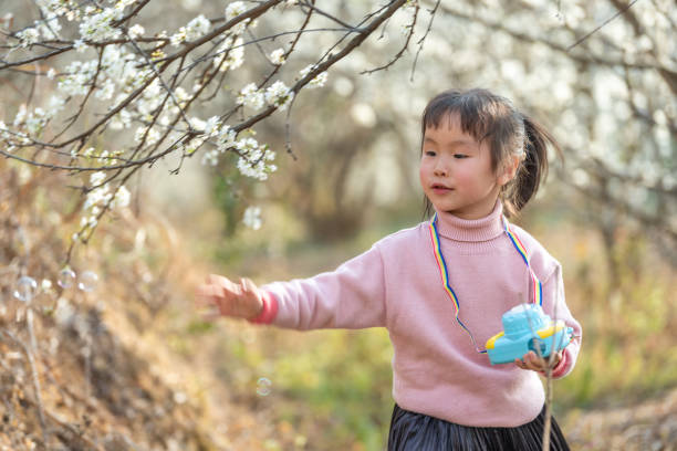 istock A little girl blowing bubbles in the blooming plum trees 1490813882