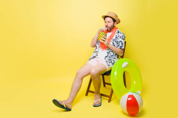 istock Relaxed man having a pineapple summer drink wearing shorts and a hat 1490814169