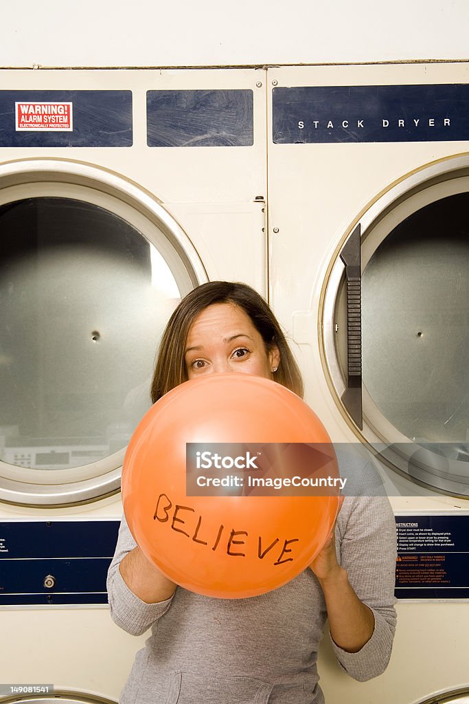 Joven mujer Soplando un globo en la lavandería. - Foto de stock de Adulto libre de derechos