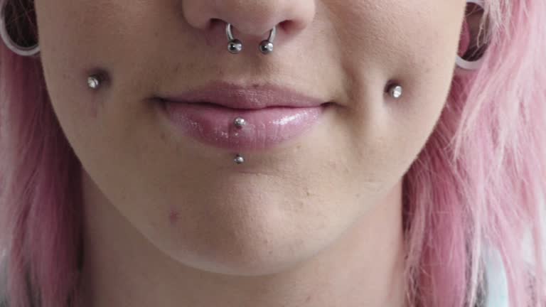 close up punk woman mouth smiling wearing piercings pink hairstyle nose ring beauty