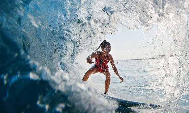 소녀 서퍼가 파도를 탄다. 빨간 양복을 입은 여자는 몰디브에서 파도를 서핑하고 배럴에 휩싸입니다. - women sensuality surfing water sport 뉴스 사진 이미지