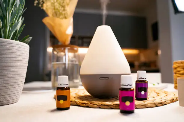Aroma therapy and air purifier. Essential oils next to diffuser working and vapor coming out of it