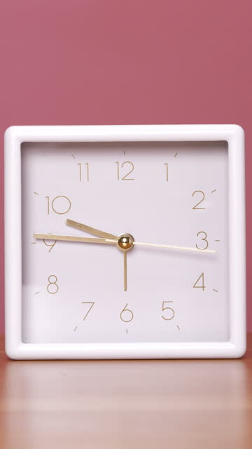 Table clock with a white square frame is rapidly turning the clock hands.