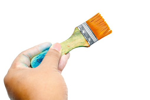 Human hand holding dirty paintbrushes isolated over white background