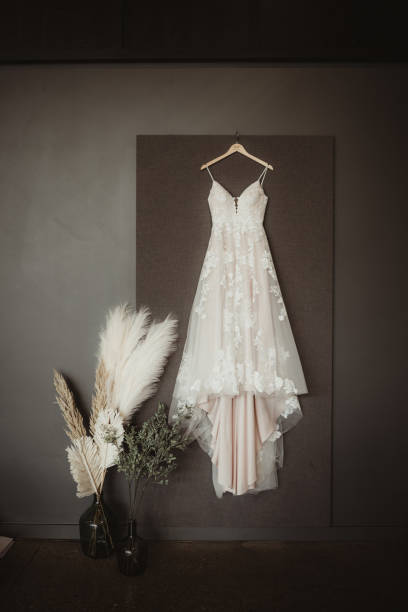istock Wedding dress hanging up on dark background with copy space 1490827722