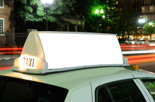 Taxi billboard close-up at night. City lights, traffic