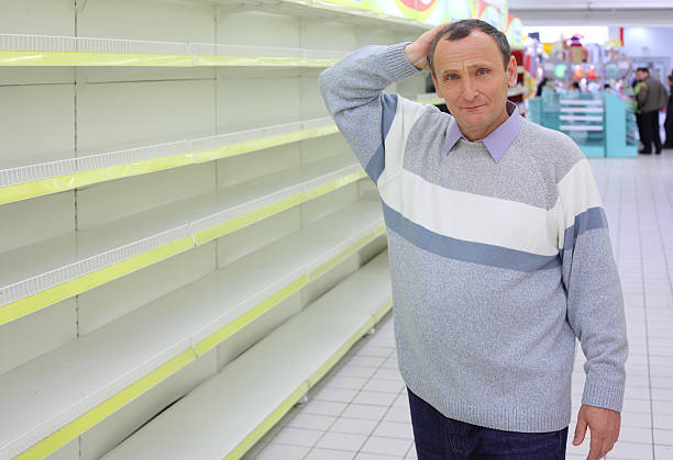 Elderly man at empty shelves in shop stock photo