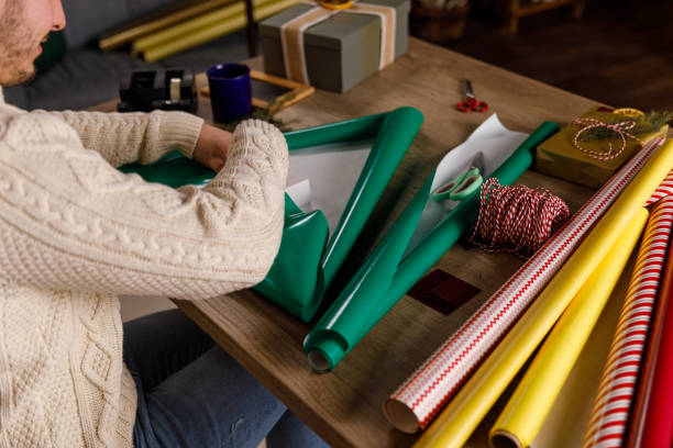 istock Neat young man wrapping a small gift box in green colored wrapping paper 1490833335