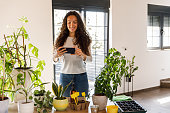 Young woman taking photos of her houseplants while tending them