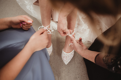 Bride putting on her wedding attire with help downward angle
