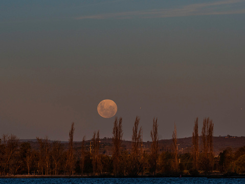 Moon rise over Lake Burley Griffith in Canberra and small plane flying