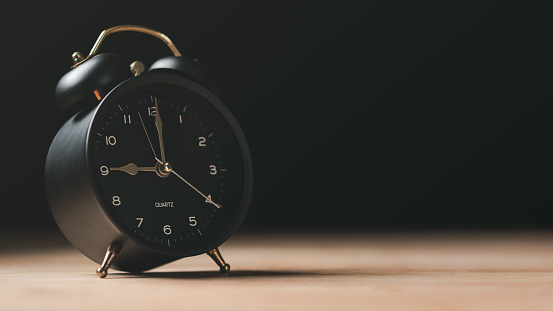 A black alarm clock sits on the table , time management concept,effective business planning,time management in the organization,Agreement and solution,end of the deal ,profitable use of time