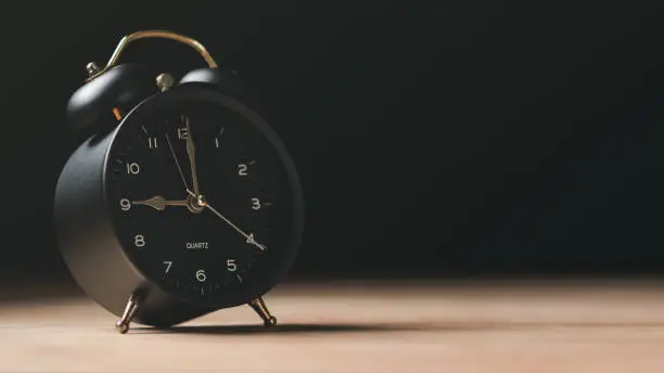 Photo of A black alarm clock sits on the table , time management concept,effective business planning,time management in the organization,Agreement and solution,end of the deal ,profitable use of time