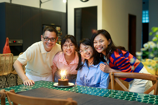 An Asian family is captured in a heartwarming moment as they give a delightful surprise and celebrate their youngest sister's birthday at home.