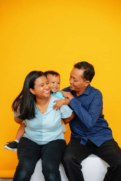 Studio Portrait of Family Mother Father Boy in front of Bright Yellow Background stock photo