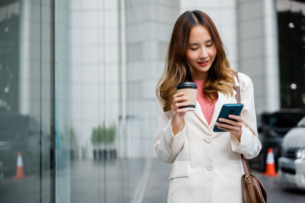 young professional woman uses her smartphone to stay connected while enjoying her coffee