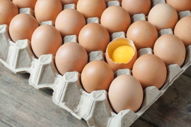 istock Chicken eggs with broken egg half with a yolk in a carton box 1490855843