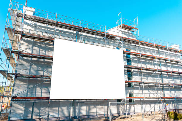 istock Advertisement billboard on scaffolding,signboard on building facade.Blank information board near the construction site with a new concrete building among scaffolding.Summer day. 1490858885